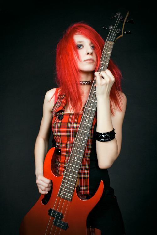 Featured Photo for "Punk Rock Bass Lessons" at Knoxville Bass Lessons depicting girl with bright red hair in a red and black plaid dress holding a red bass guitar